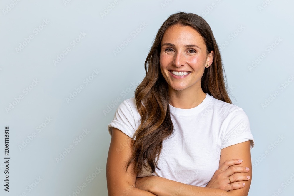 Fototapeta premium The Confident Smiling Woman Portrait in a White Tee Against Soft Blue Background