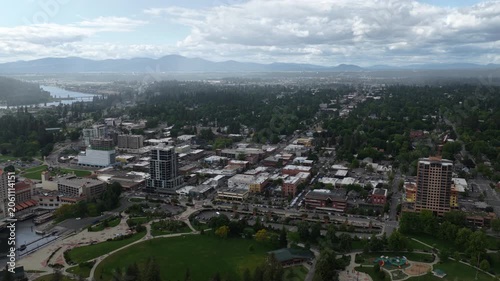 Wide Aerial of Coeur dAlene Idaho urban downtown landscape with mountains in spring showing a mix of developed areas green spaces and distant mountain ranges under cloudy skies