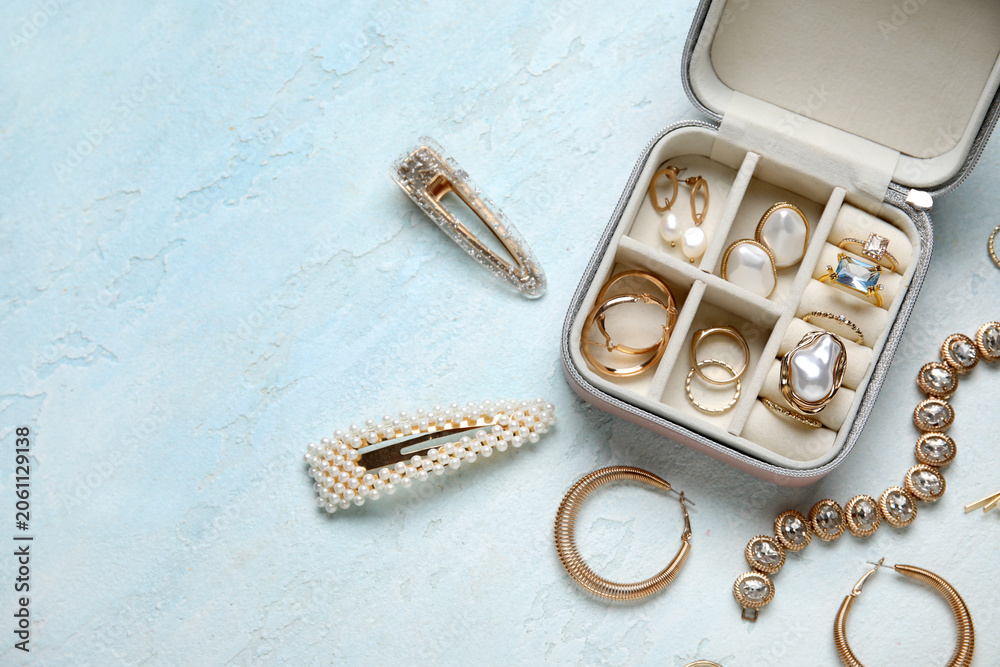 Obraz premium Open organizer with different golden jewelry on light blue background