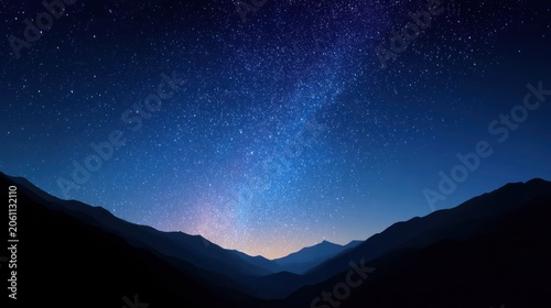 Brilliant stars illuminate the deep blue night sky above layered mountain silhouettes.