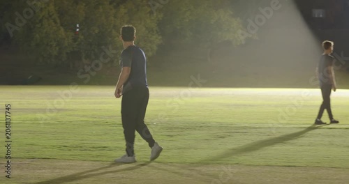 Umpire signaling bowler bowling under lights batsman missing shot fielder returning ball