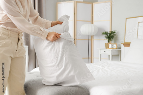Young woman putting pillow ...