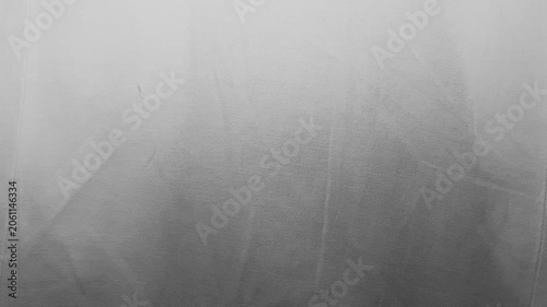 white fabric texture waving gently in soft cinematic lighting creating monochrome abstract shadows