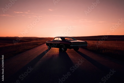 Golden hour scene with a timeless car silhouette on the road