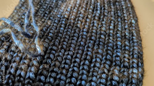 Close-up blue warm shiny crochet fabric with visible stitch pattern, handmade hobby craft