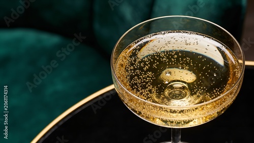 Elegant crystal glass filled with sparkling golden champagne showing tiny rising bubbles captured from a high angle view in a sophisticated luxury bar setting at night