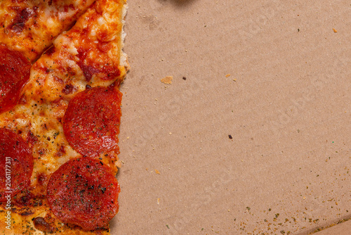 Detailed top down macro view of pepperoni pizza slices inside a cardboard delivery box.
