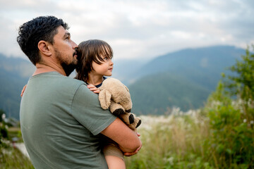 Father carrying son with teddy bear at vacation