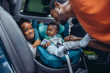 Father looking at son and daughter sitting in car
