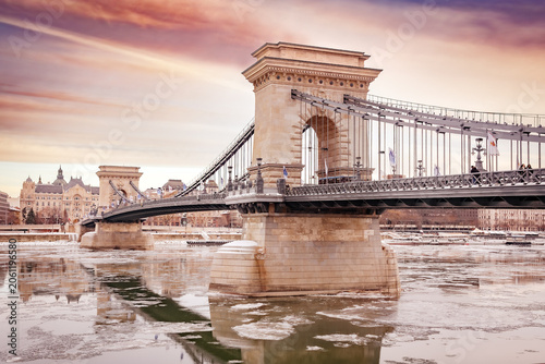 Szechenyi Chain Bridge over the frozen Danube river at dramatic sunset, Budapest, Hungary