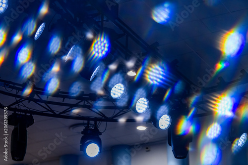 Stage lights glowing with bright colorful lens flare on dark background. Disco spotlights creating vibrant prism light effect.