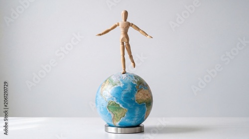 Global balance concept with wooden figure on earth globe