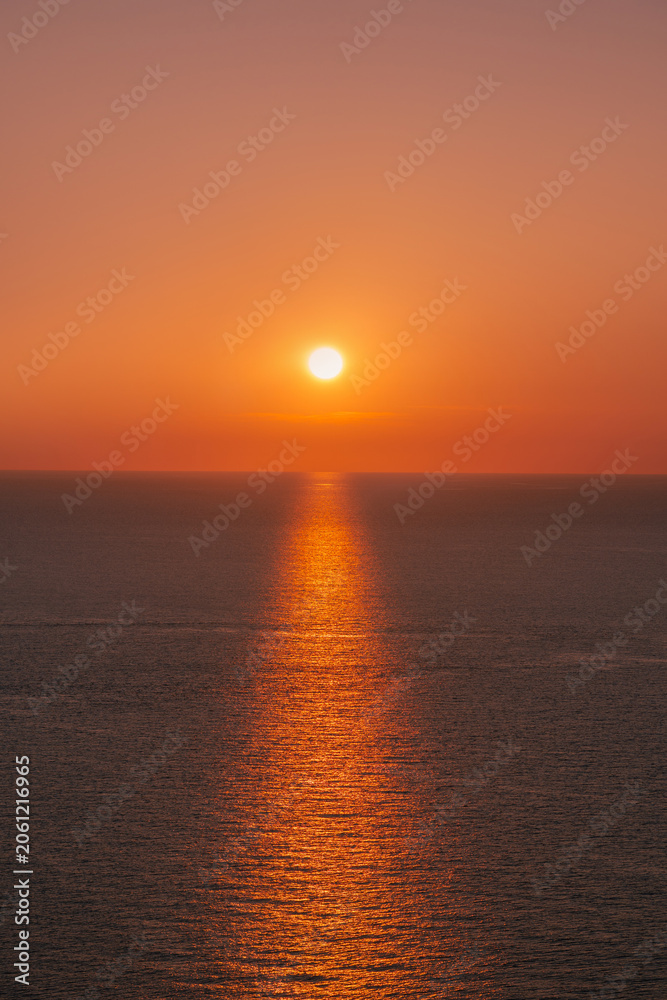 Fototapeta premium Bright sun setting over the calm Mediterranean sea horizon in Menorca coast