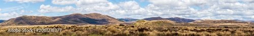 Expansive Mountainous Grasslands Under Clouded Sky