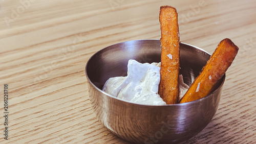close up of sweet potato fries in creamy dipping sauce