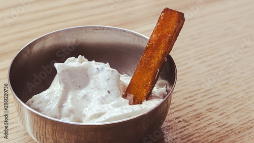 close up of sweet potato fry dipped in creamy white sauce
