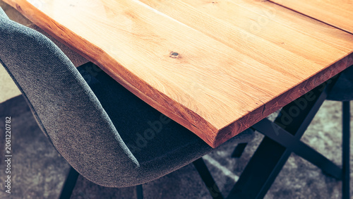 close up of modern wooden dining table and grey fabric chair