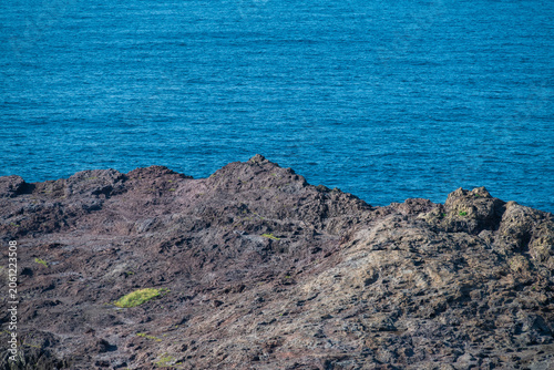 Konstfotografi Jagged rocky coastline meeting the deep blue sea