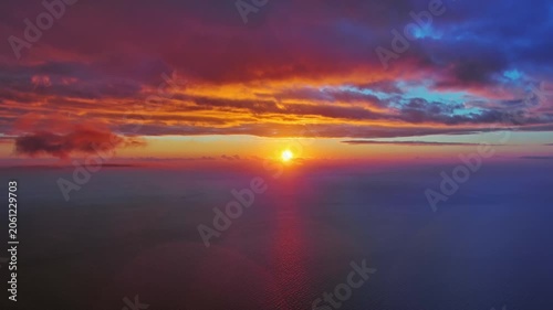 Aerial view of bright sun setting over calm sea. Scenic view of ocean horizon with dramatic clouds. Natural landscape background, 4k