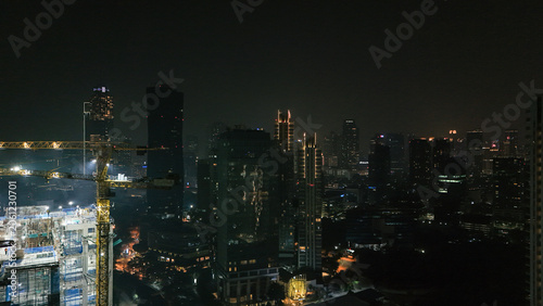 Illuminated Construction Crane Operates At Night Overlooking Sprawling Urban Skyline