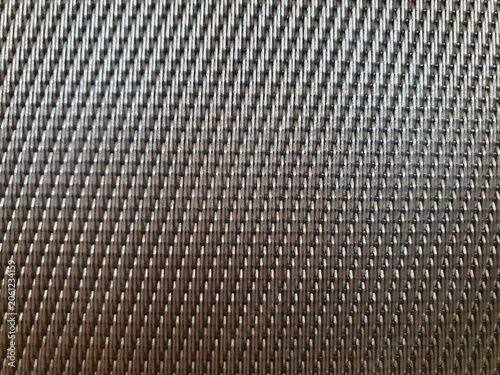 Phone photo of a brown woven plastic texture. Close-up abstract scene showing pattern, material detail, and tactile surface.
