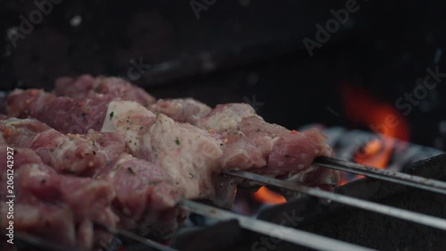 Fresh marinated meat grilling on metal skewers over hot charcoal and open flame