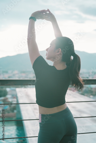 Fotografie Asian woman stretching arms up, finding balance and well-being on an urban rooft