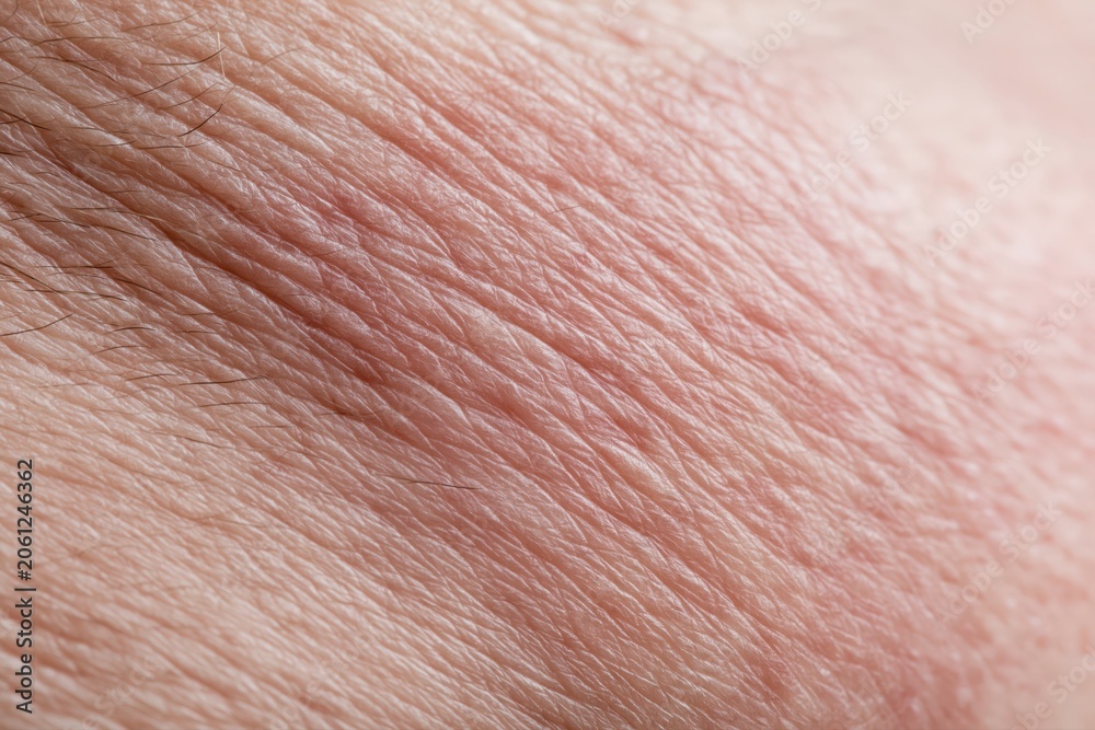 Fototapeta premium Extreme close-up macro shot of human skin texture with fine wrinkles and sparse dark hairs visible.