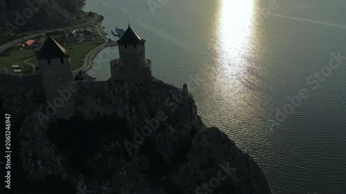 Aerial around view of Golubac medieval fortress on cliff above Danube river at sunset, historic landmark in Serbia, 4k