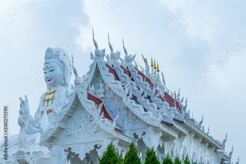 Photography Giant white Guan Yin statue sitting on a lotus pedestal on green hill under beautiful blue sky at Wat Huay Pla Kang, Chiang Rai, Thailand