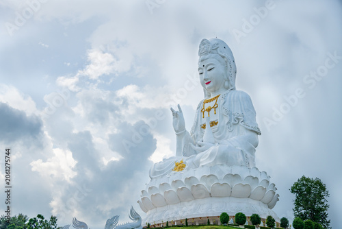 Obraz na plátně Giant white Guan Yin statue sitting on a lotus pedestal on green hill under beautiful blue sky at Wat Huay Pla Kang, Chiang Rai, Thailand