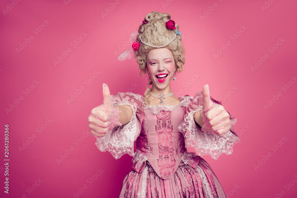 Fototapeta premium Photo of excited lady princess blinking eye making thumb up symbol wear medieval theme costume isolated pink color background
