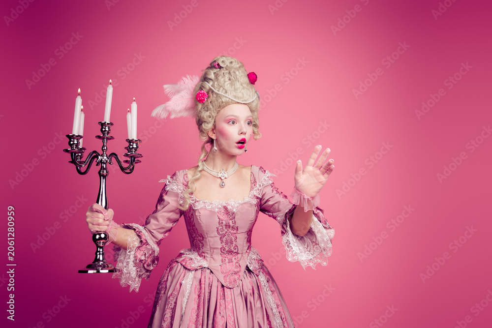 Fototapeta premium Photo of surprised lady medieval princess wonder castle with candle stick hold hands wear dress corset isolated pink color background