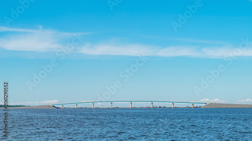 Modern concrete sea bridge structure near Hailuoto island in Oulu, Finland. Minimalist landscape with a distant bridge over the blue sea under a clear sky with copy space.