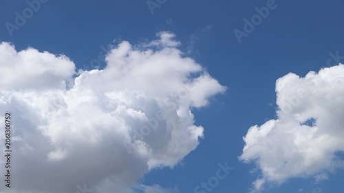 Large white clouds drift across a bright blue sky on a clear day.