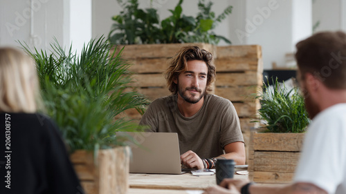 Young entrepreneur eco startup office laptop teamwork plant meeting workspace young team planning sustainable business in sunlit office