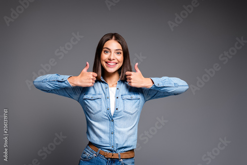 Εκτύπωση καμβά Young woman in denim shirt giving double thumbs up with a bright smile, positive