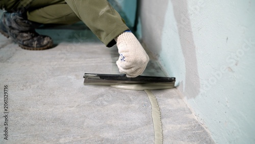 Construction worker applying sealant to floor joint with trowel