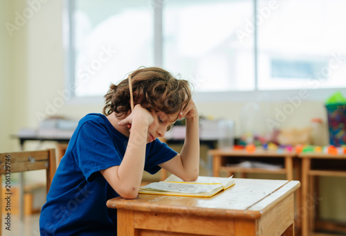 Fotografie Bored student boy leaning head on hands during school lesson in classroom settin