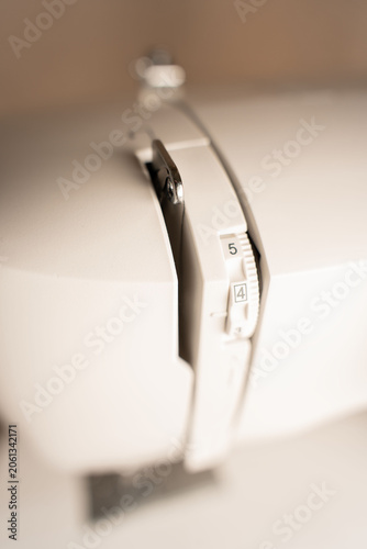Fotografie extreme close-up of a white domestic sewing machine presser foot and numbered te