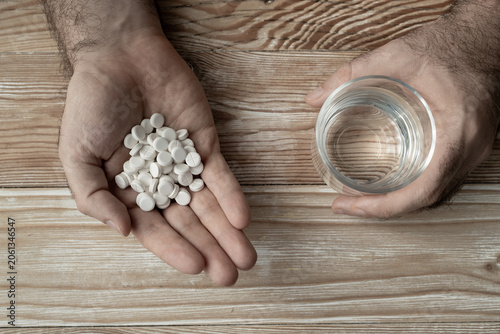 Pills in hand top view, taking painkillers, white medical tablets