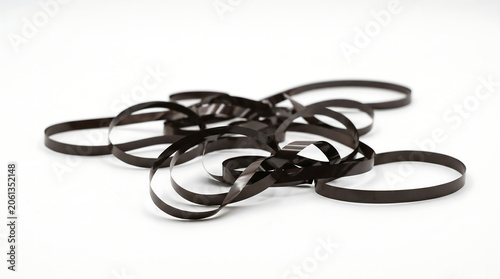Tangled pile of vintage magnetic audio cassette tape unspooled on a clean white background