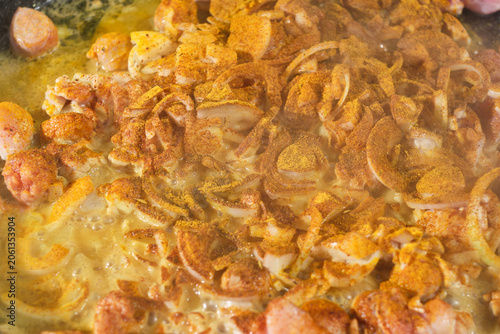 Cooking paella with chicken, vegetables in a frying pan and sprinkled with turmeric. Large paella pan being served outdoors. Hot Vibrant Spanish Paella. Selective focus.