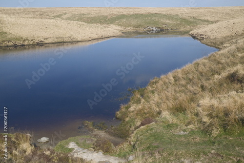 Pinkery Pond on Exmoor, Devon in late winter, with deep blue water and pale moor grasses; dramatic moorland landscape