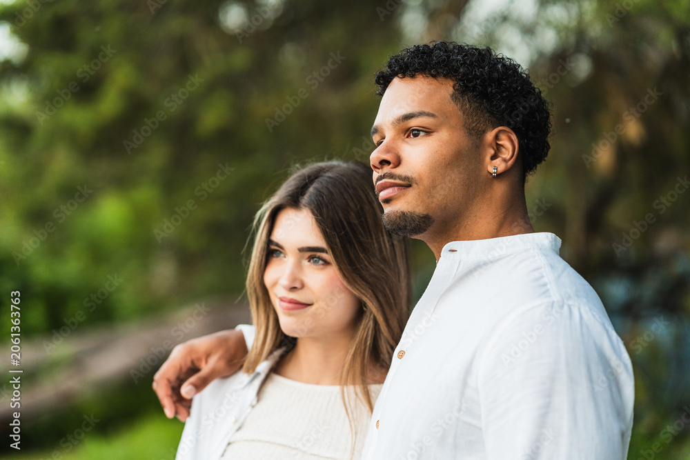 Fototapeta premium Young couple embracing, looking into the distance, finding happiness and connection on their journey in nature