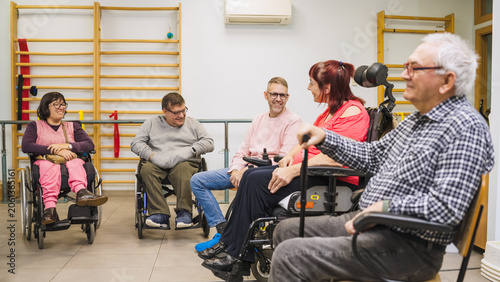 Group of adults with physical disabilities sitting in rehabilitation center, actively participating and connecting