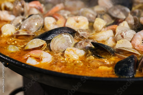 Cooking paella with seafood, and vegetables in a frying pan. Hot Vibrant Spanish Paella. Selective focus.