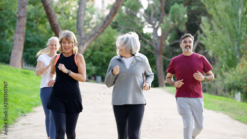 Fotografie Senior friends jogging together on a sunny park path, staying active and healthy