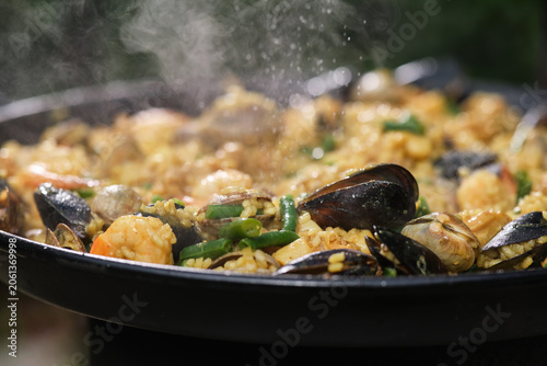 Cooking paella with chicken, seafood, and vegetables in a frying pan. Hot Vibrant Spanish Paella. Selective focus.