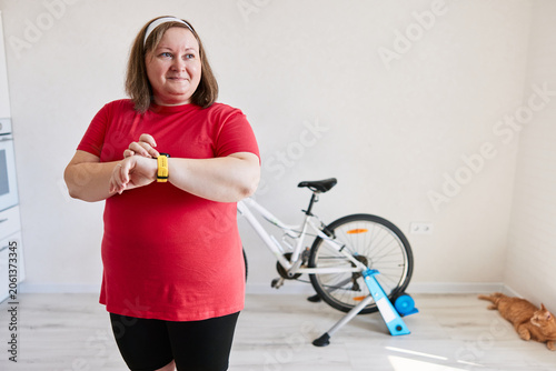 Woman using smart watch for home bike training